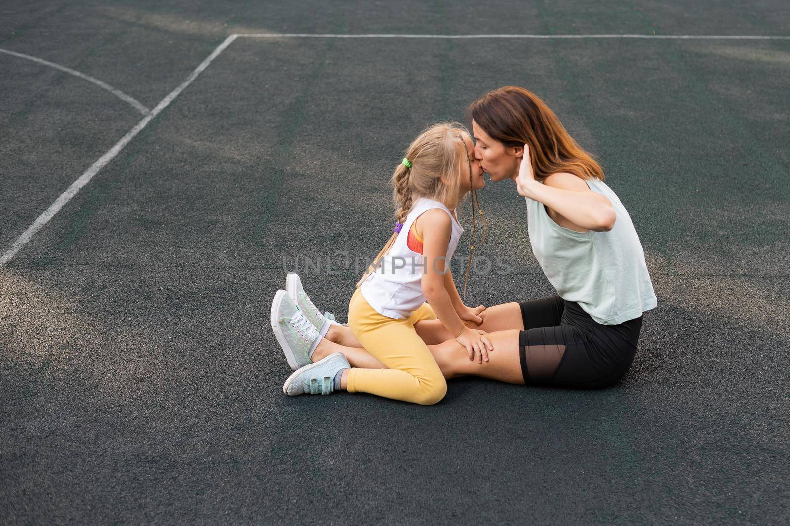 Mother and daughter go in for sports outdoors. Caucasian woman and little girl are engaged in fitness at the stadium. by mrwed54