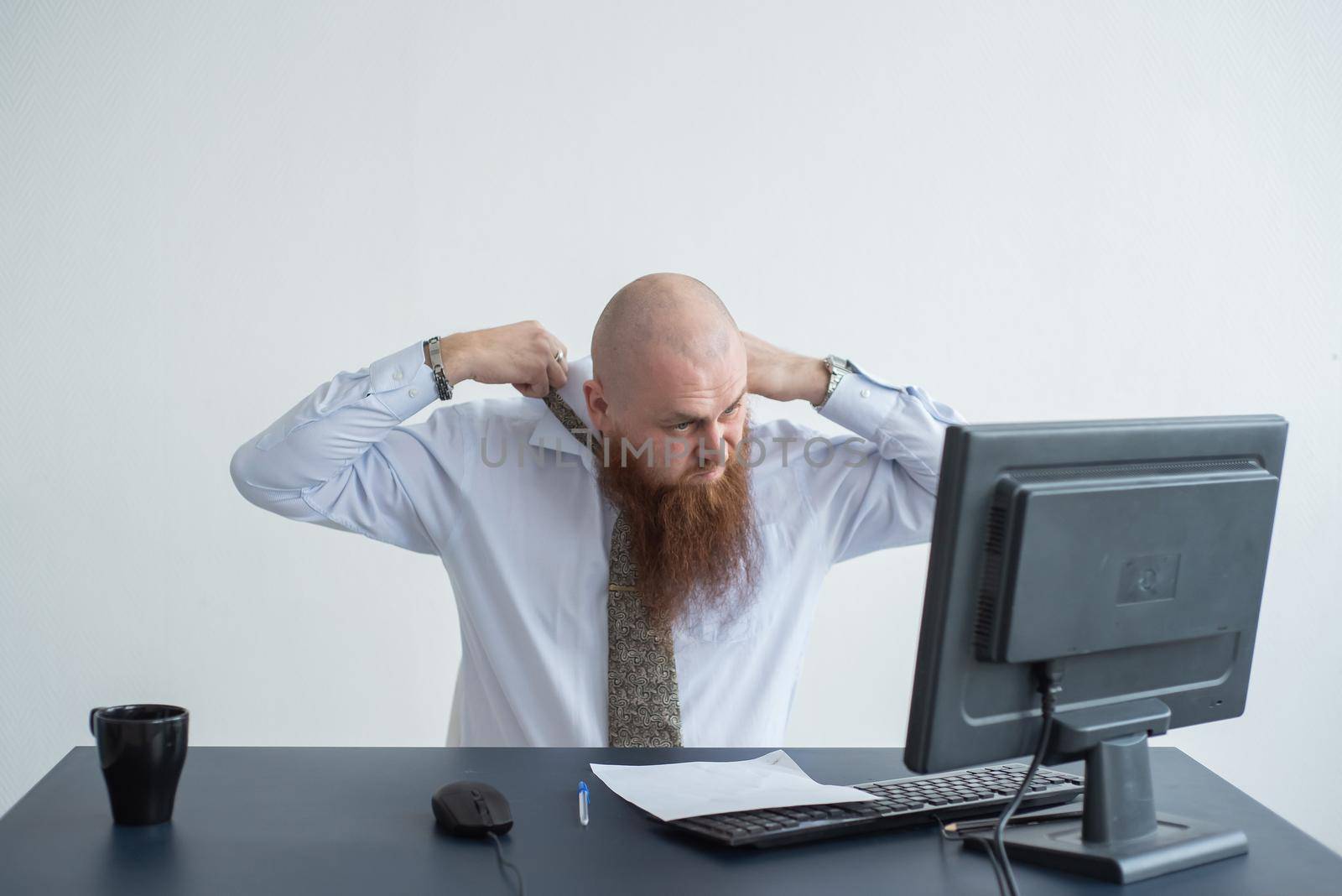 Problems for the office worker. A bald man in a white shirt sits at a desk with a computer and is stressed because of failure. A nervous breakdown