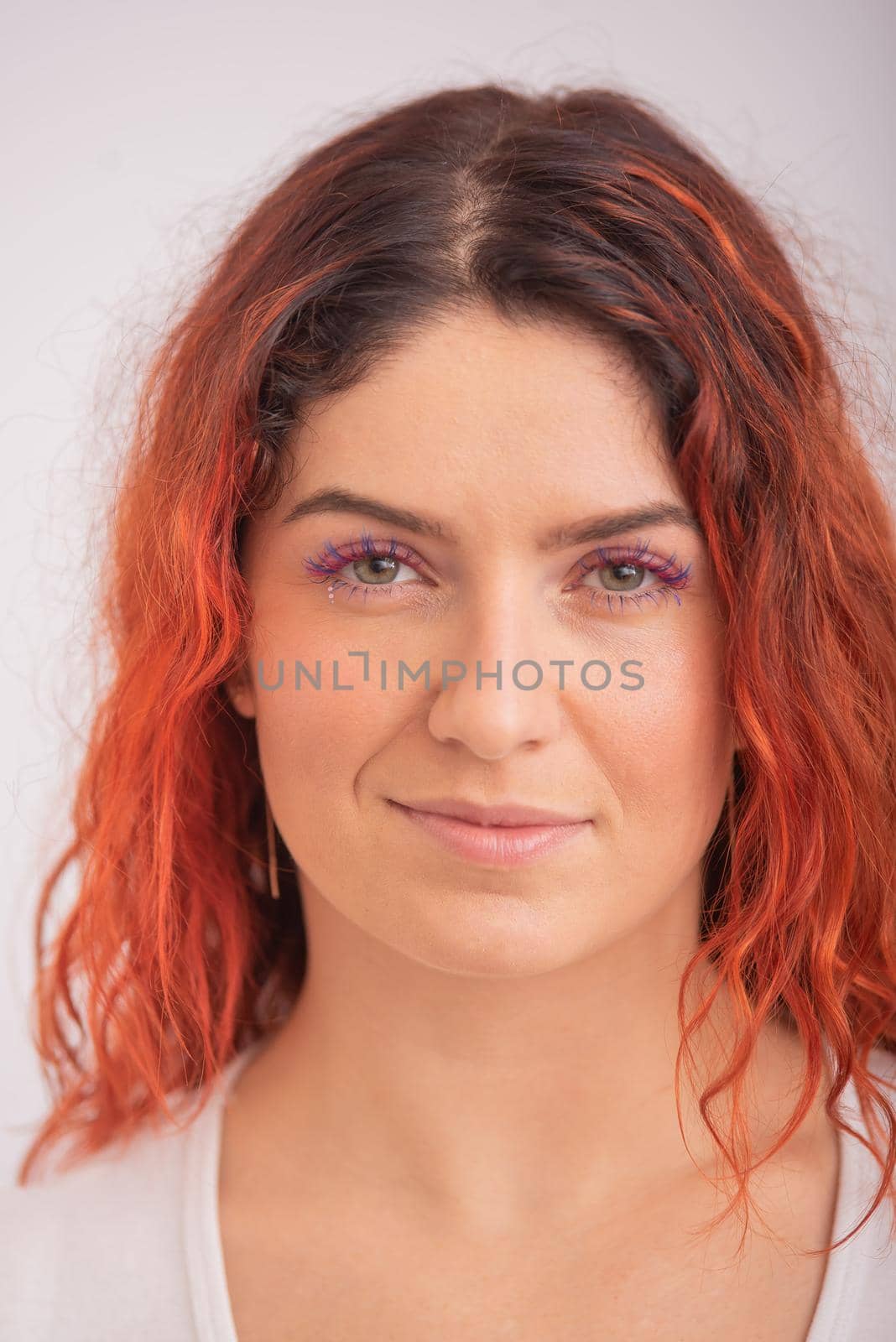 Portrait of caucasian red-haired woman with colored eyelashes on white background