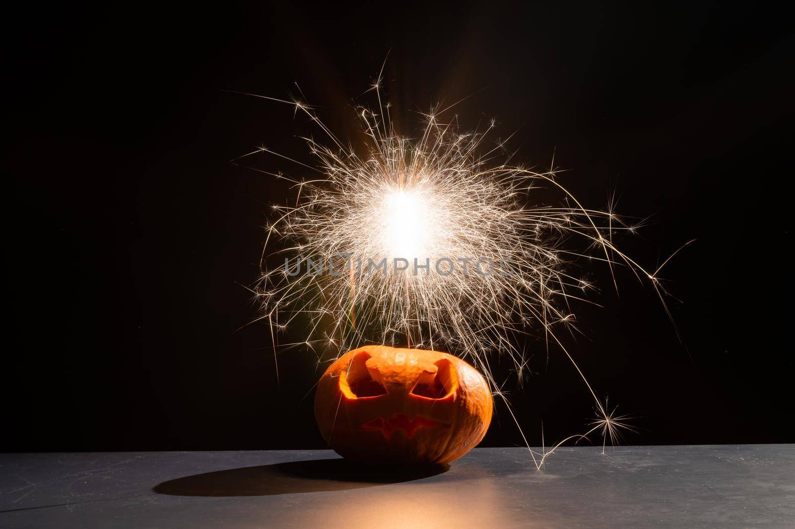 Halloween pumpkin with scary carved grimace and sparklers. jack-o-lantern.