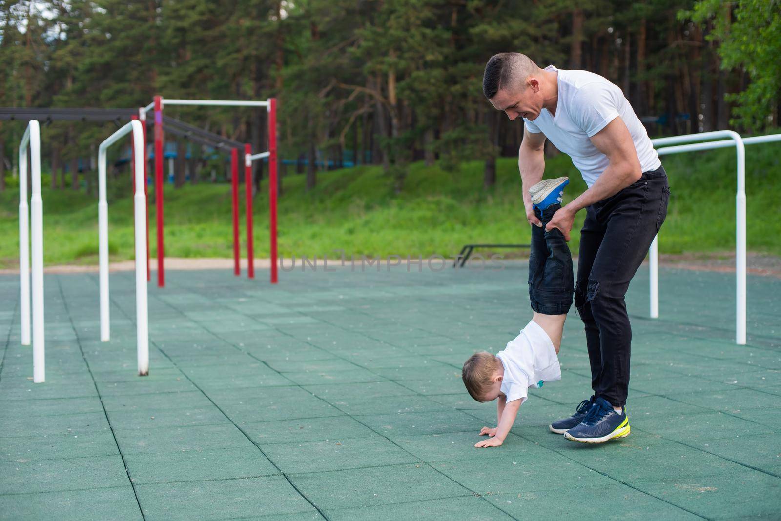 Caucasian man teaching son handstand at playground