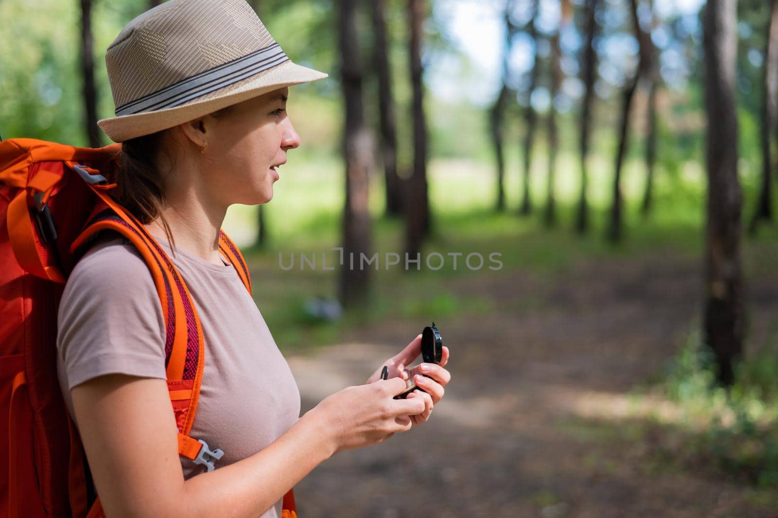 Young caucasian woman is hiking and using a compass in the forest. by mrwed54