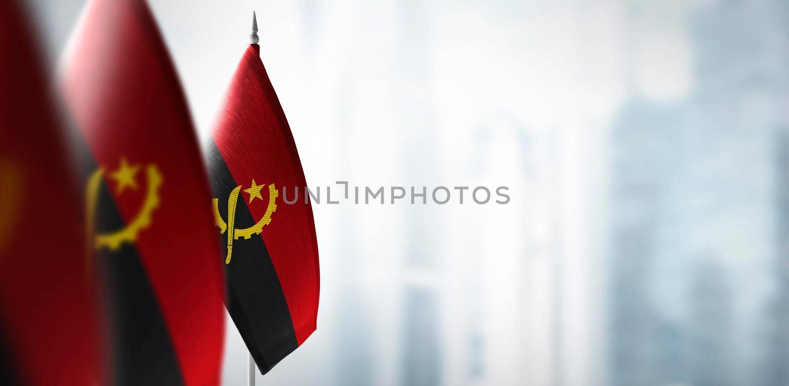 Small flags of Angola on a blurry background of the city.