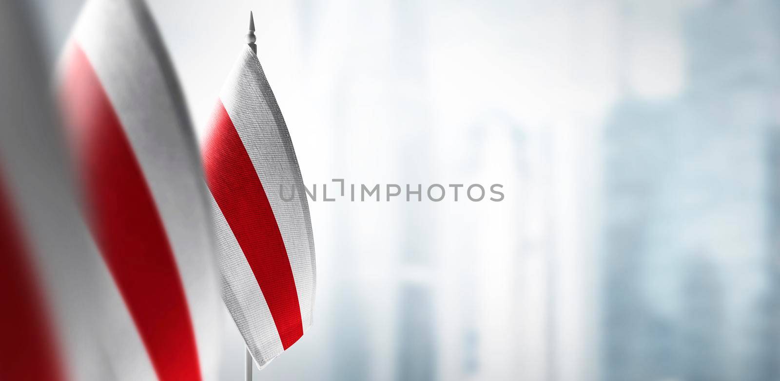 Small flags of Belarus on a blurry background of the city.