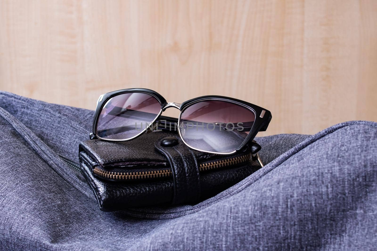 Wallet, sunglasses and travel bag on a wooden background
