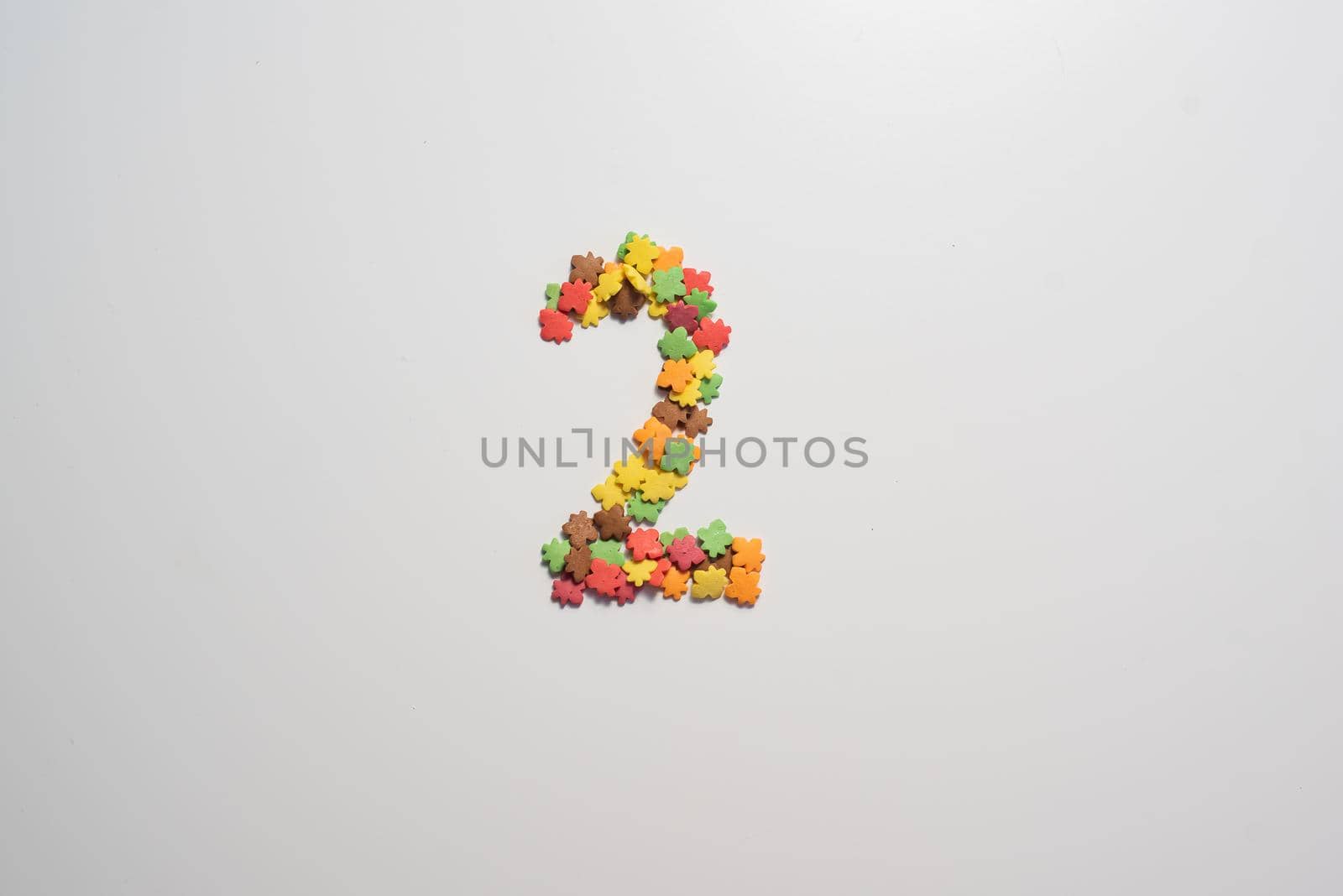 Numeral two from sweet pastry topping in the form of colorful foliage on a white background. by mrwed54