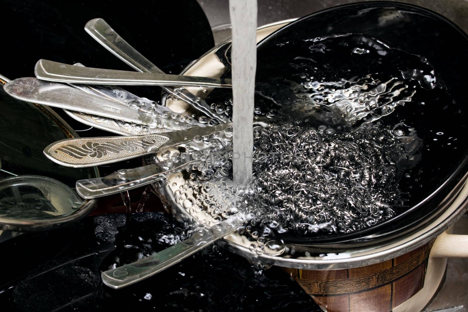 Black dishes and forks in the sink close up
