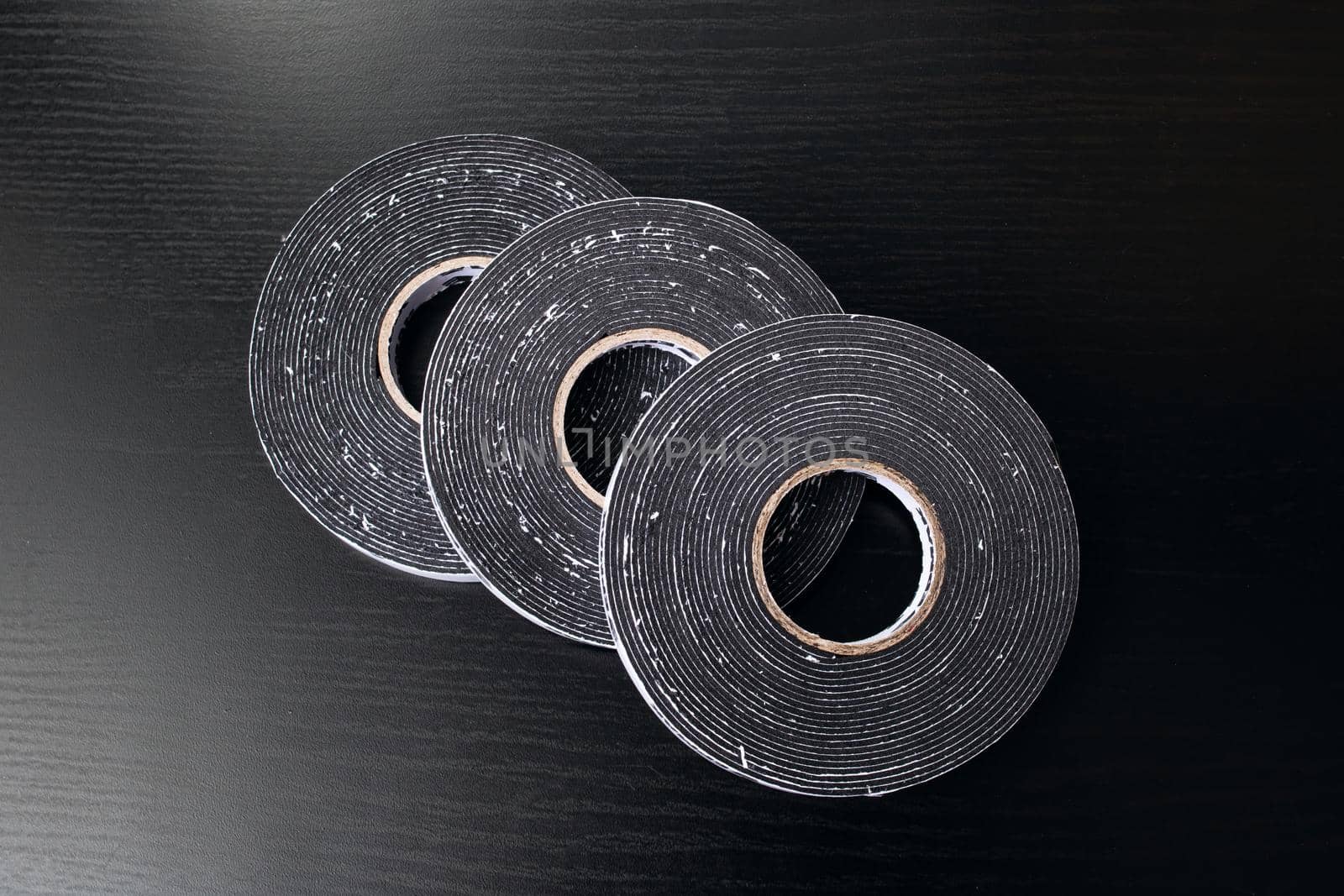 Three reels of double-sided tape on a wooden table