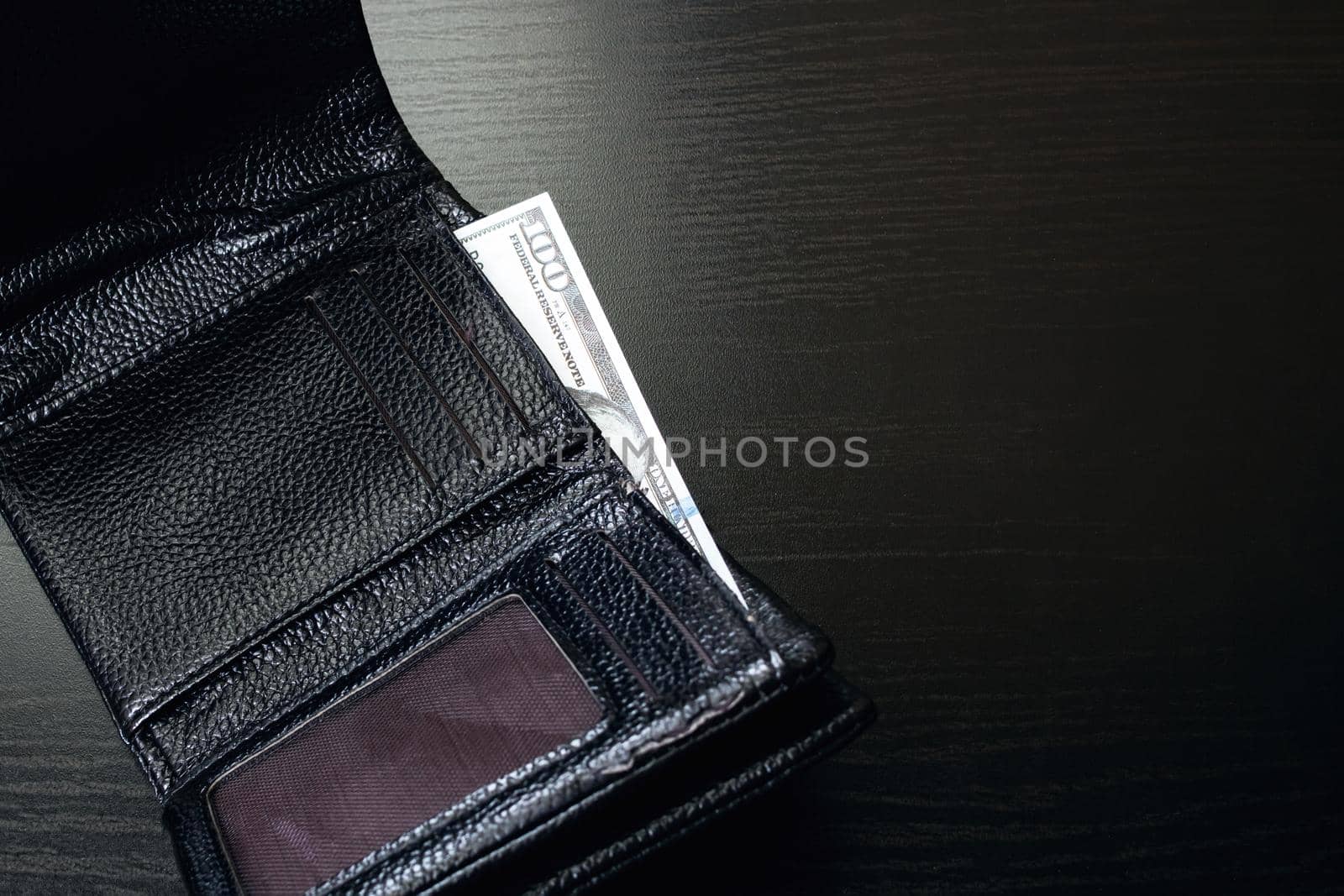 One hundred dollar bill in a black wallet
