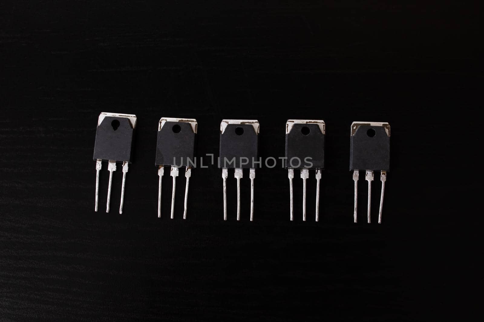 Black transistors on a black wooden table close up