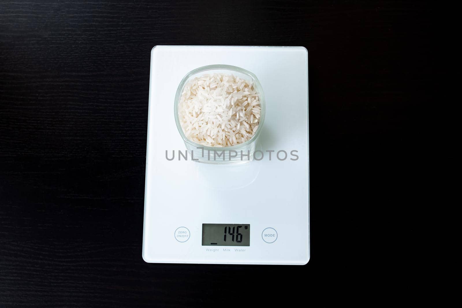 Glass with rice on electronic scales on a wooden table