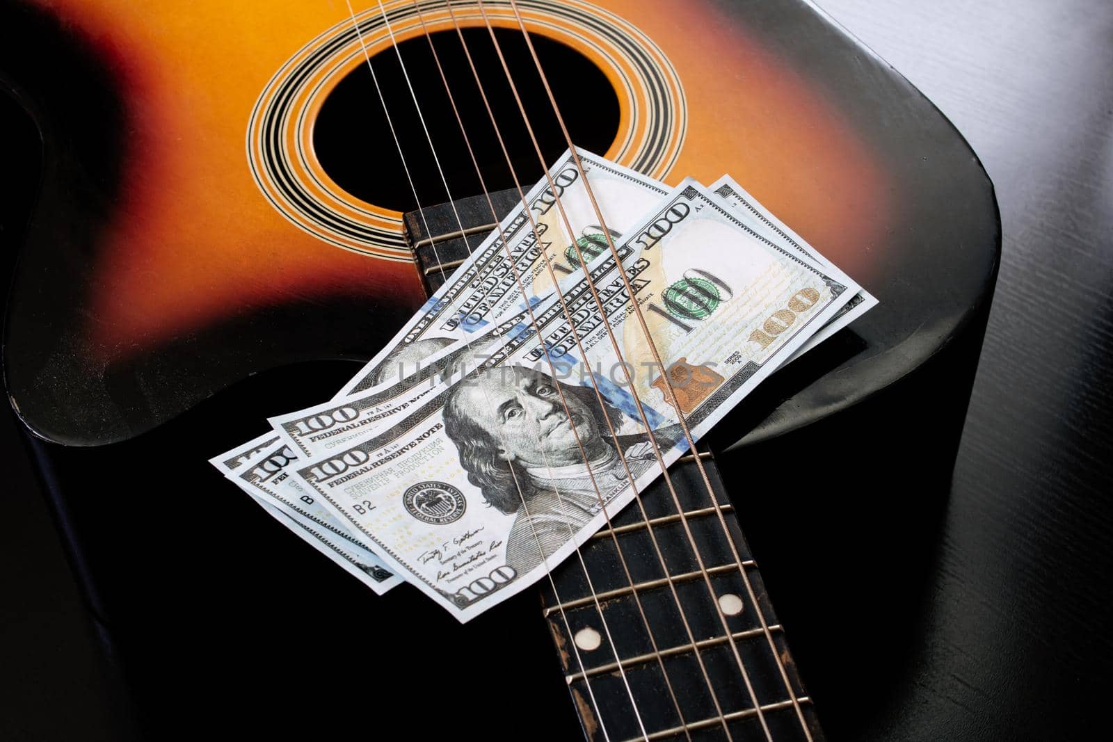 Dollar bills on an acoustic guitar close up