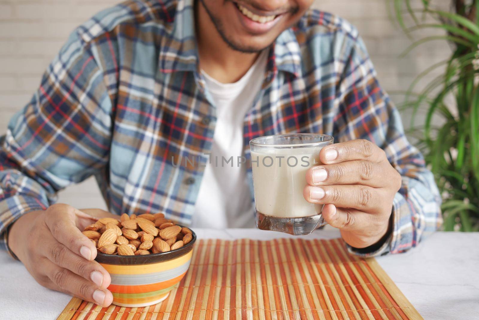 young man hand hold a glass of milk and almond nut by towfiq007