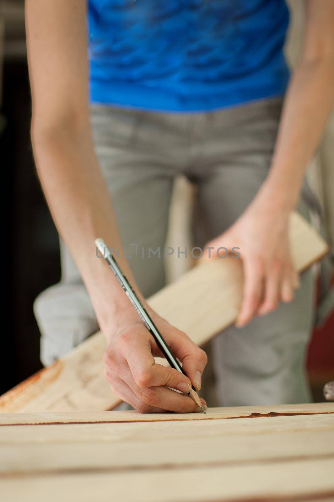 Female hands are making some marks on wooden plank for future holes using pencil for assembling bench, gender equality, feminism, do it yourself concepts. by balinska_lv