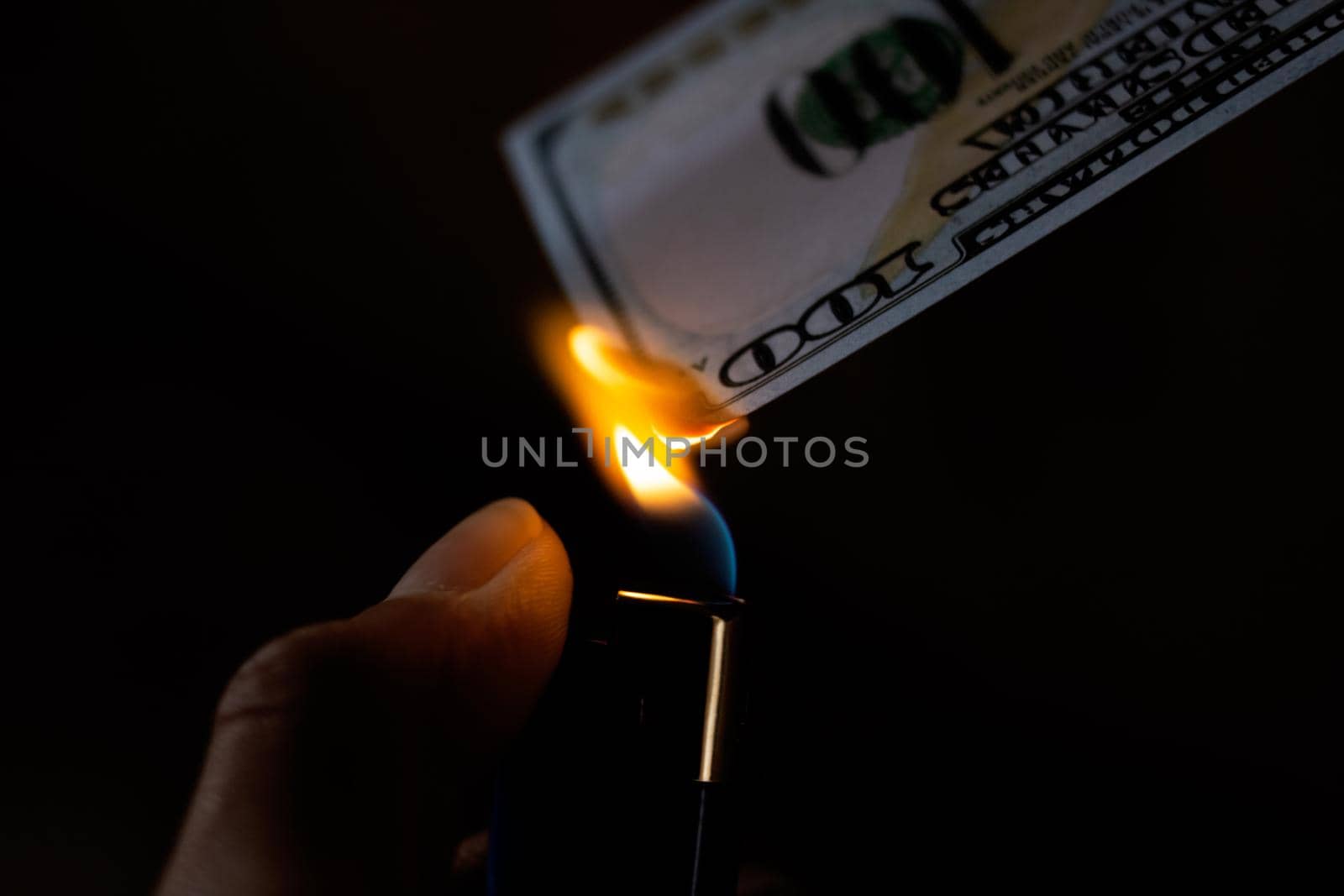 Burning dollar and lighter in hand close up
