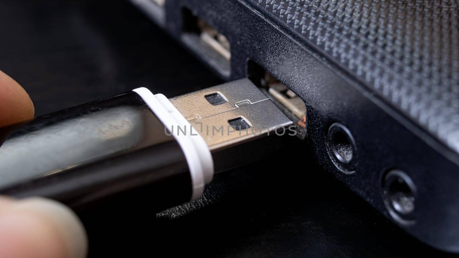 Black USB flashcard in hand and laptop close up