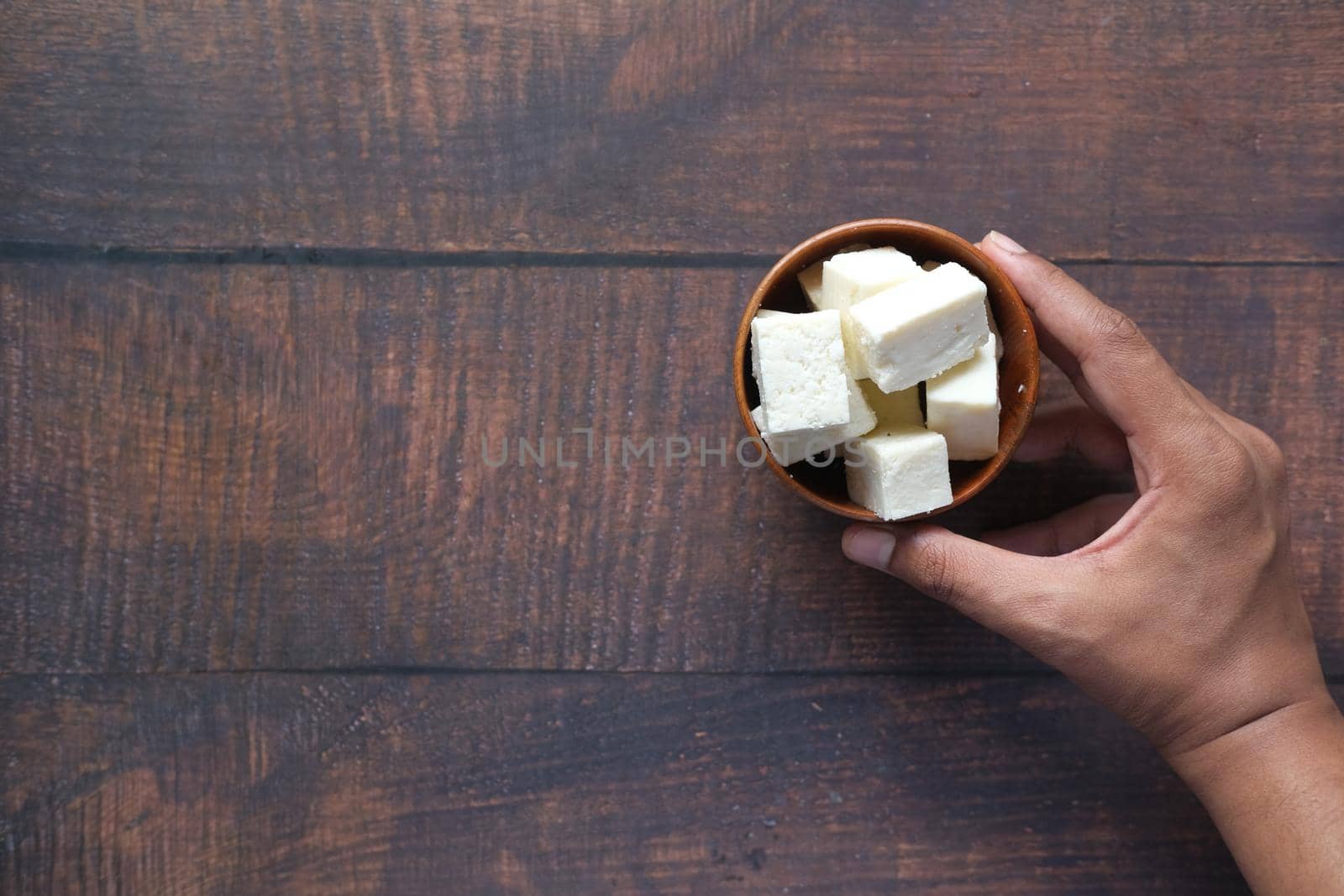 man hand holding a bowl of cheese on table .