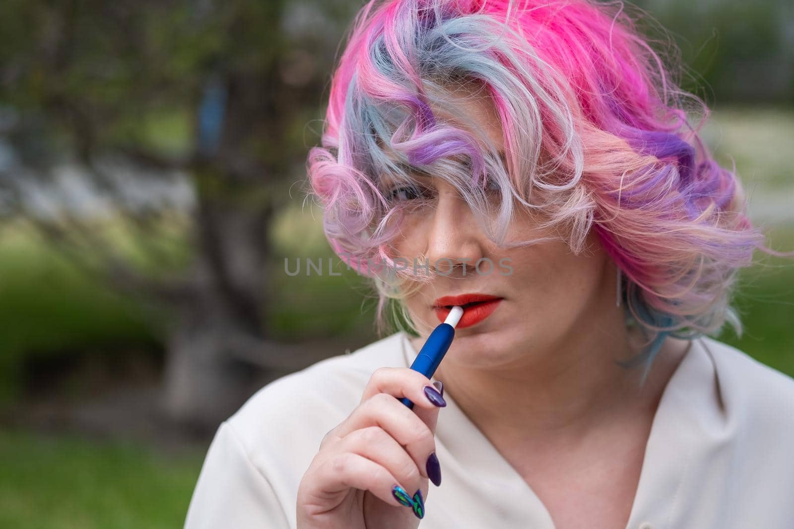 Caucasian woman with colored hair smokes an electronic cigarette