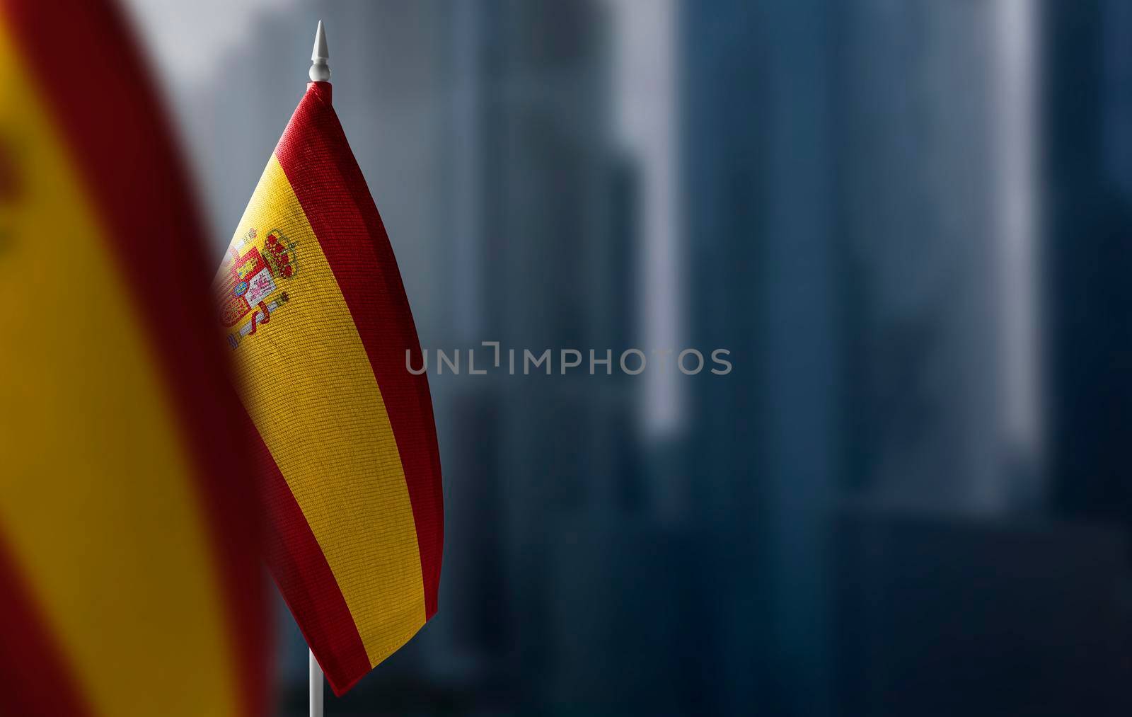 Small flags of Spain on a blurry background of the city.
