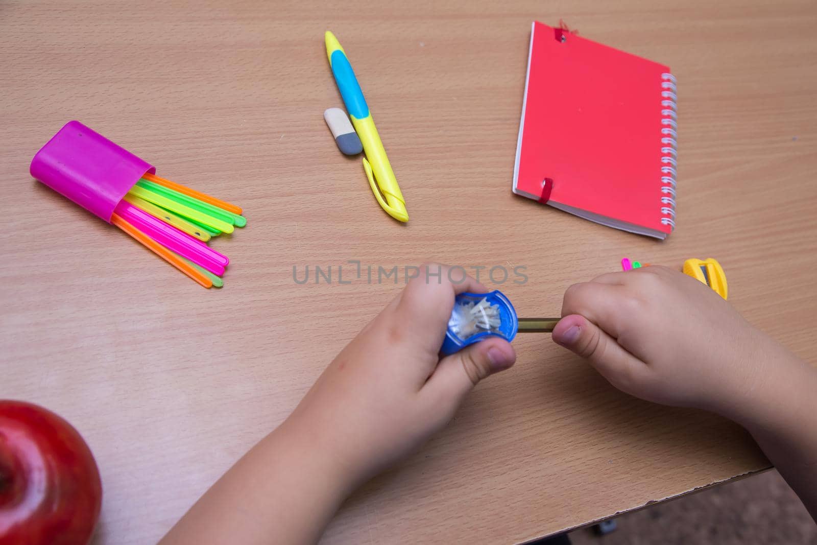 Close-up hands of a student sharpen a pencil. A schoolboy performs a task at the workplace. The concept of children's education, teaching knowledge, skills and abilities.