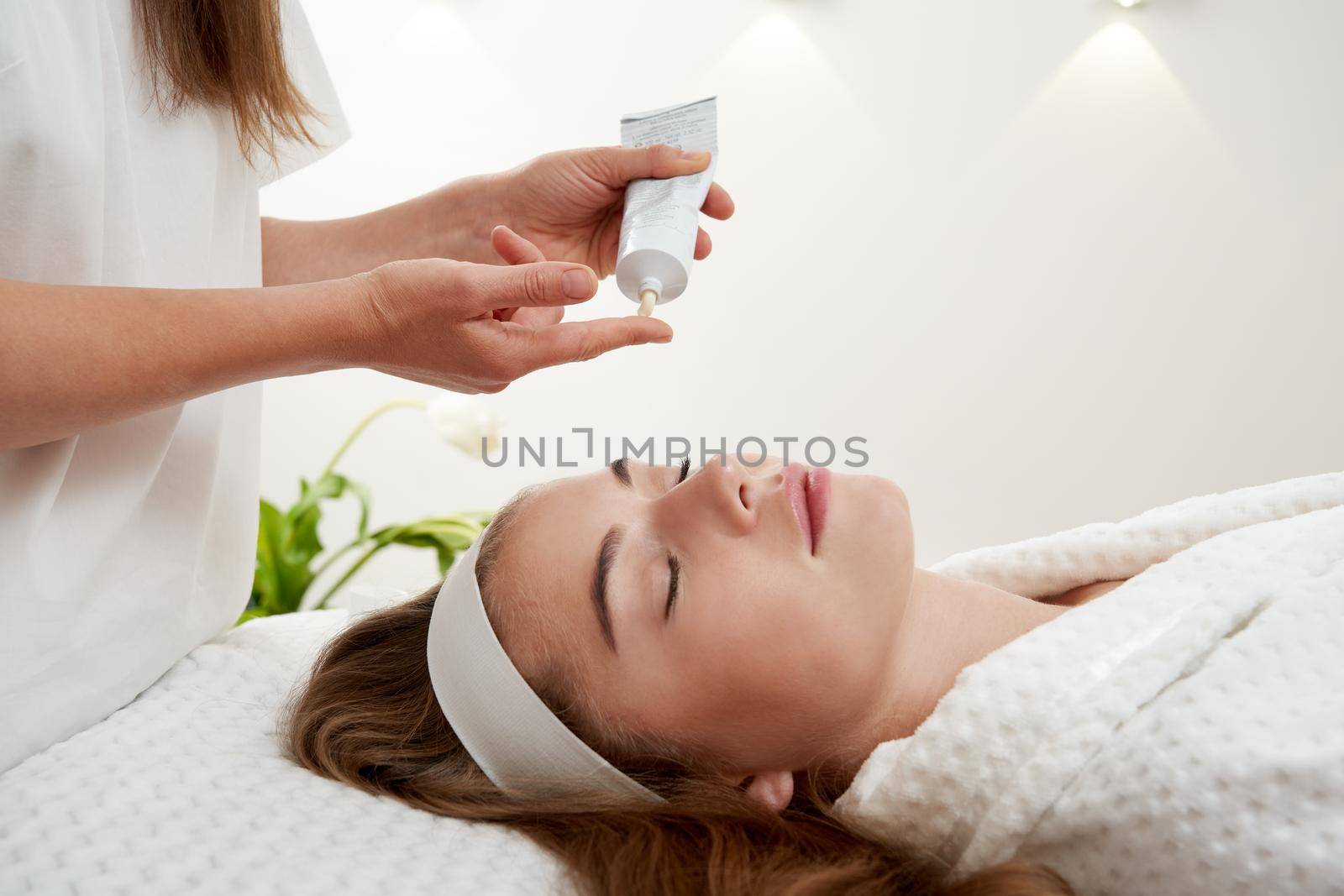 Cosmetologist applying cream on patient face, portrait closeup view. Woman in beauty clinic with doctor beautician