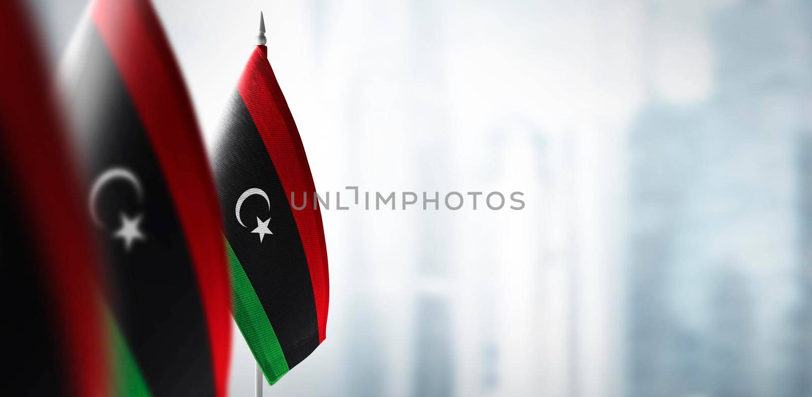 Small flags of Libya on a blurry background of the city by butenkow