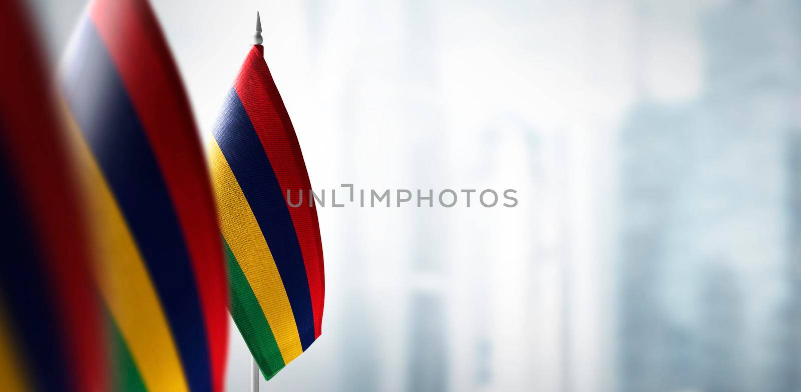 Small flags of Mauritius on a blurry background of the city by butenkow