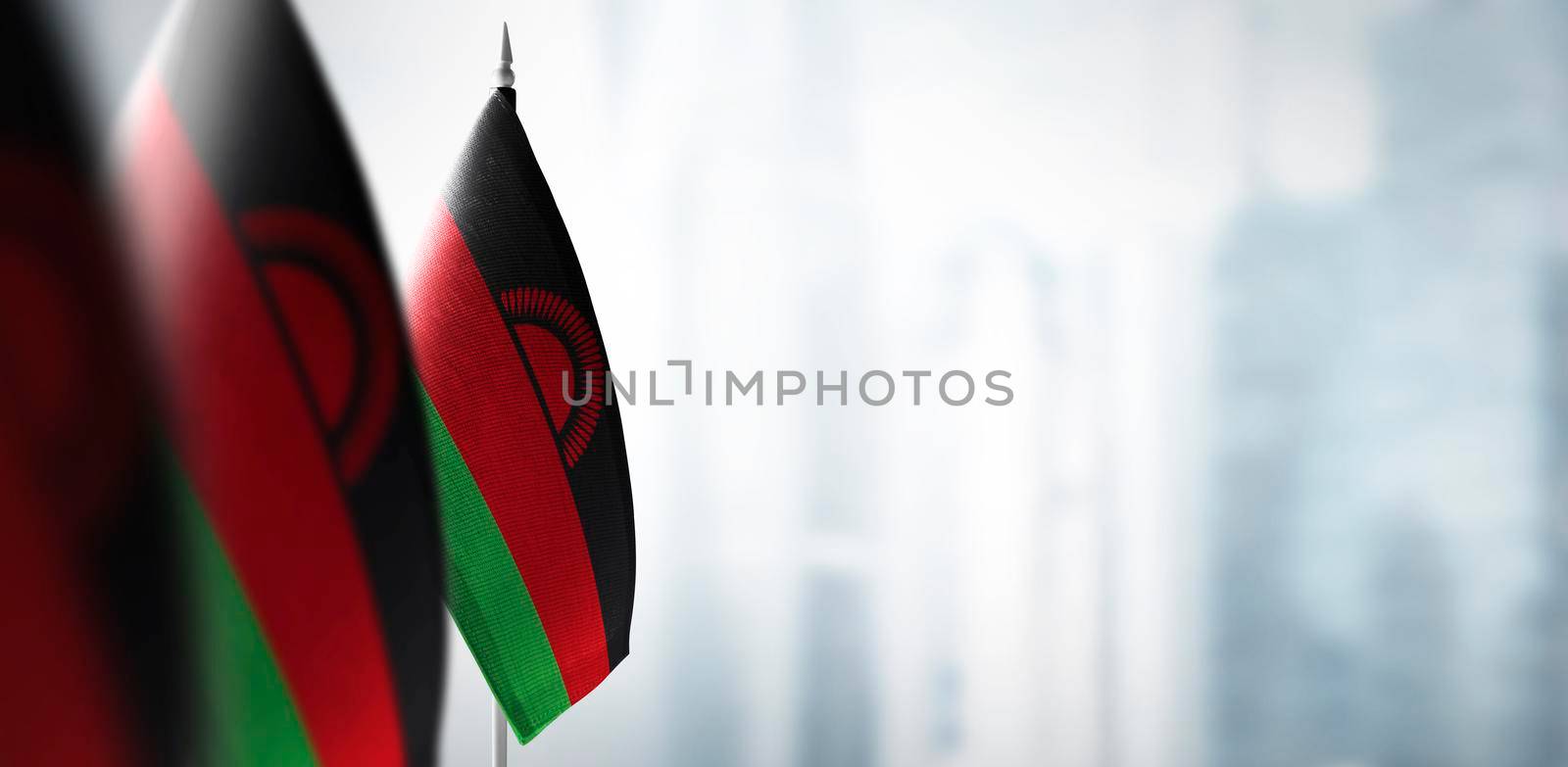 Small flags of Malawi on a blurry background of the city.