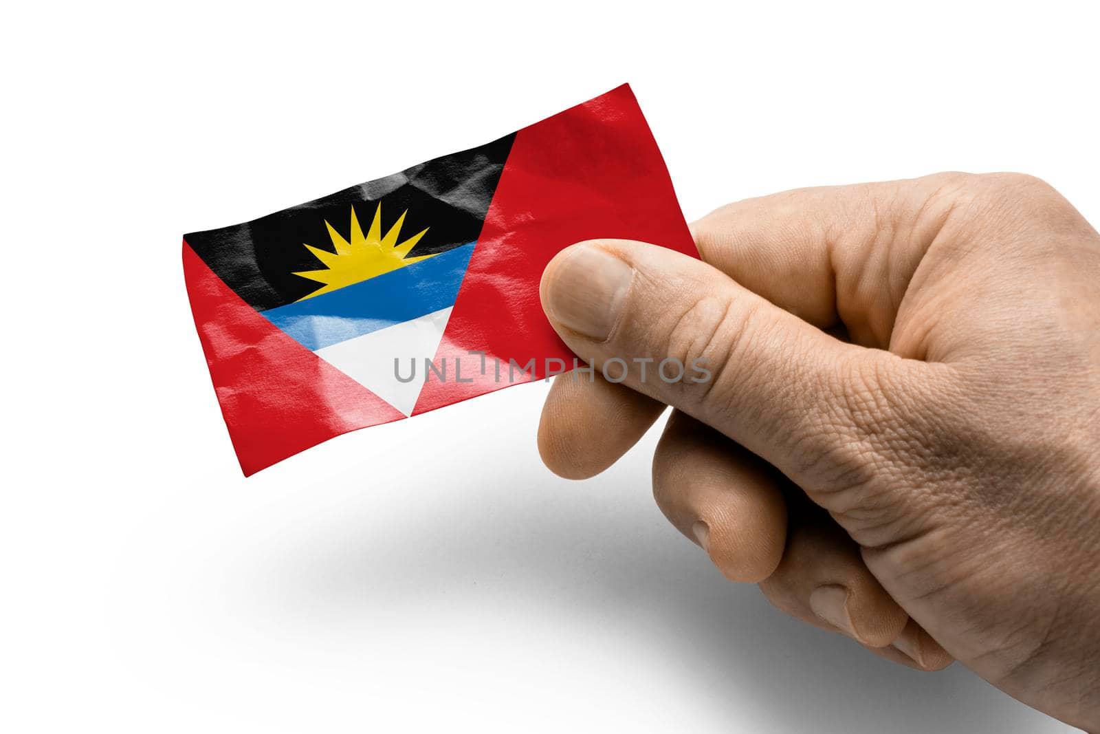 Hand holding a card with a national flag the Antigua and Barbuda.