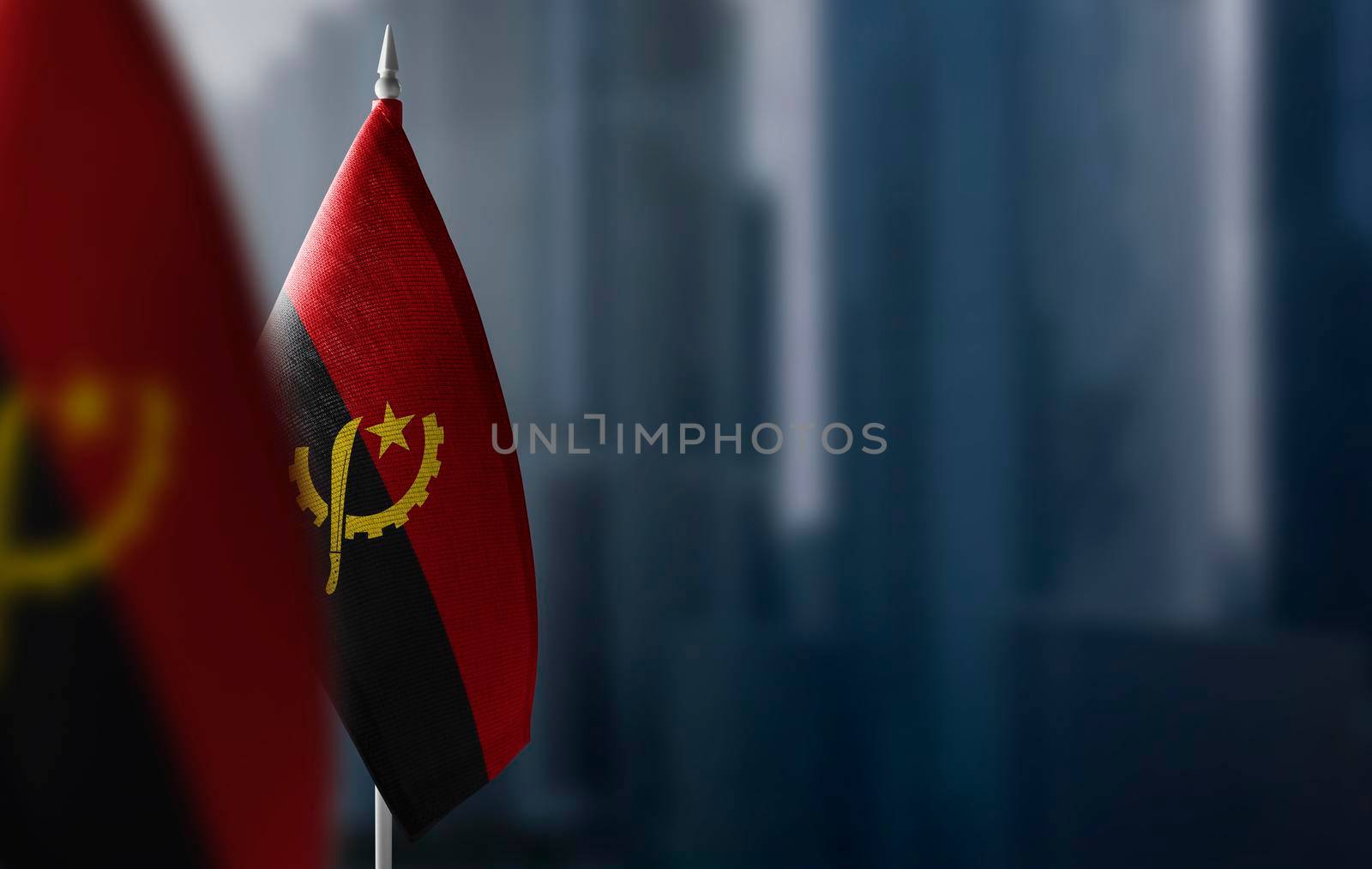 Small flags of Angola on a blurry background of the city.