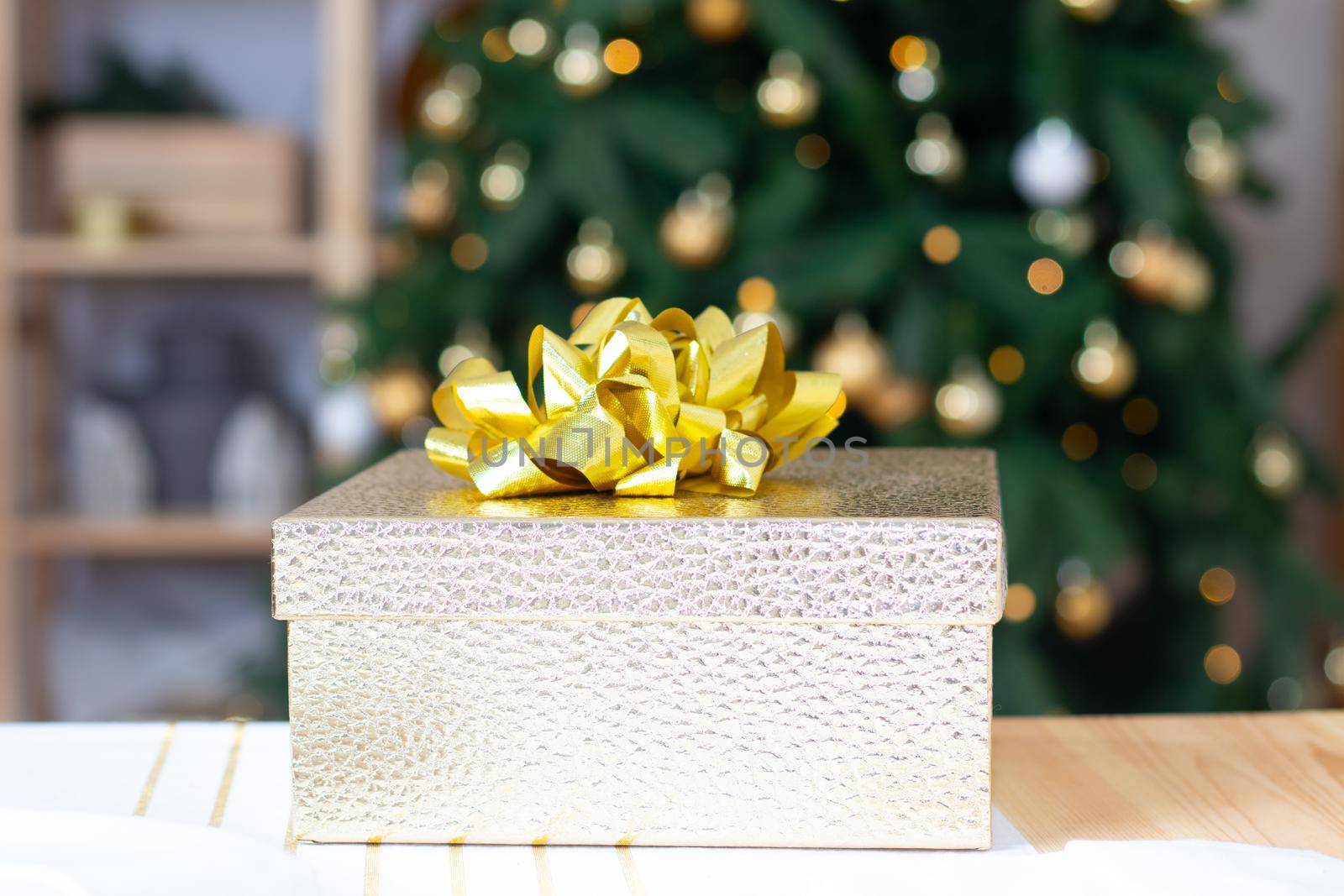 A New Year's gift on the background of a Christmas tree . New Year and Christmas. Gifts for the holiday. Festive mood. A Christmas tree. Bokeh. Copy Space