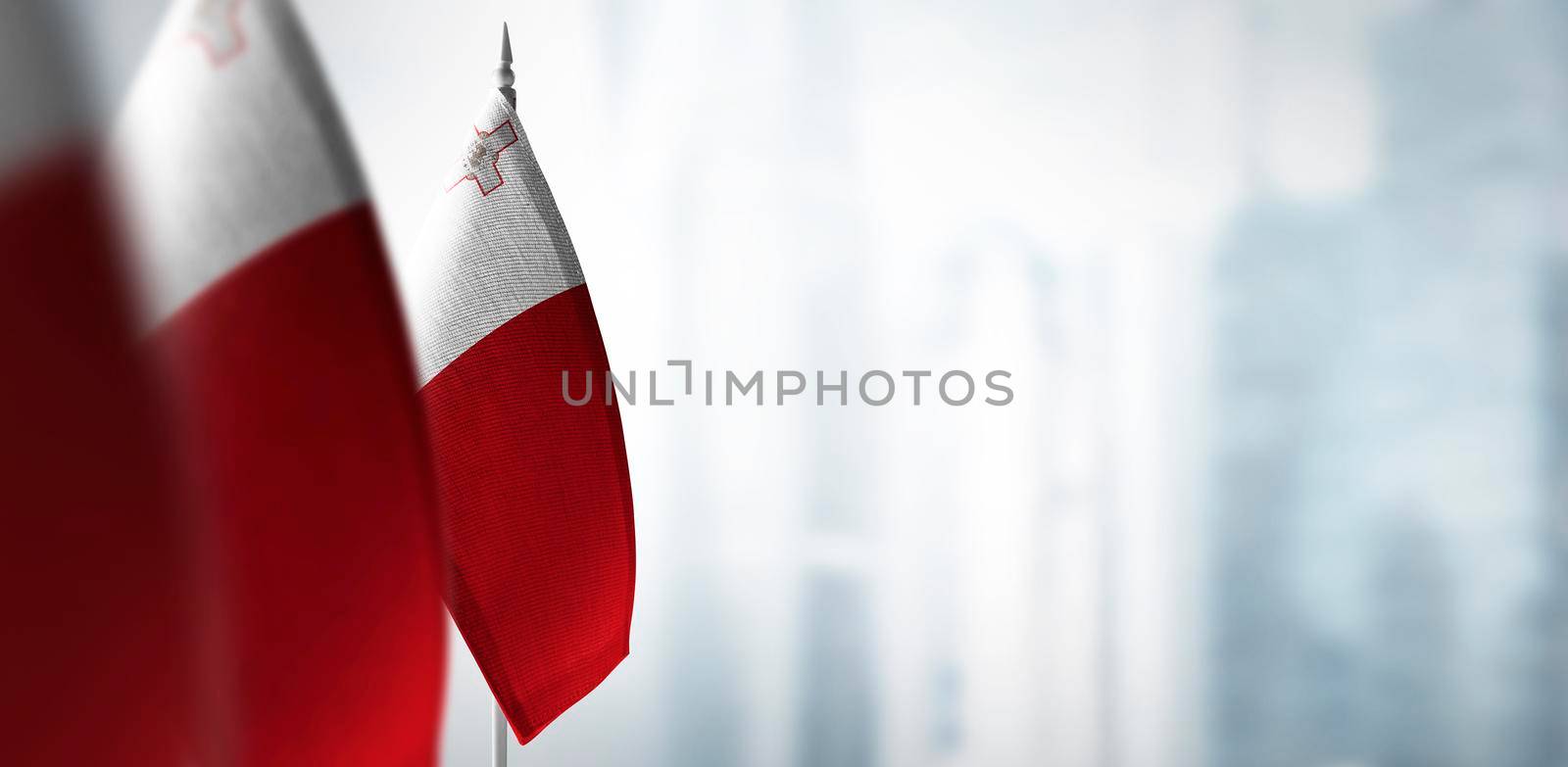Small flags of Malta on a blurry background of the city.