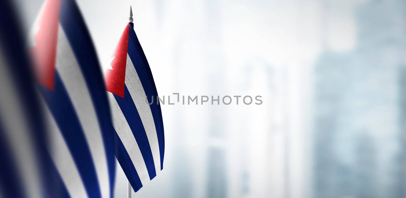 Small flags of Cuba on a blurry background of the city.