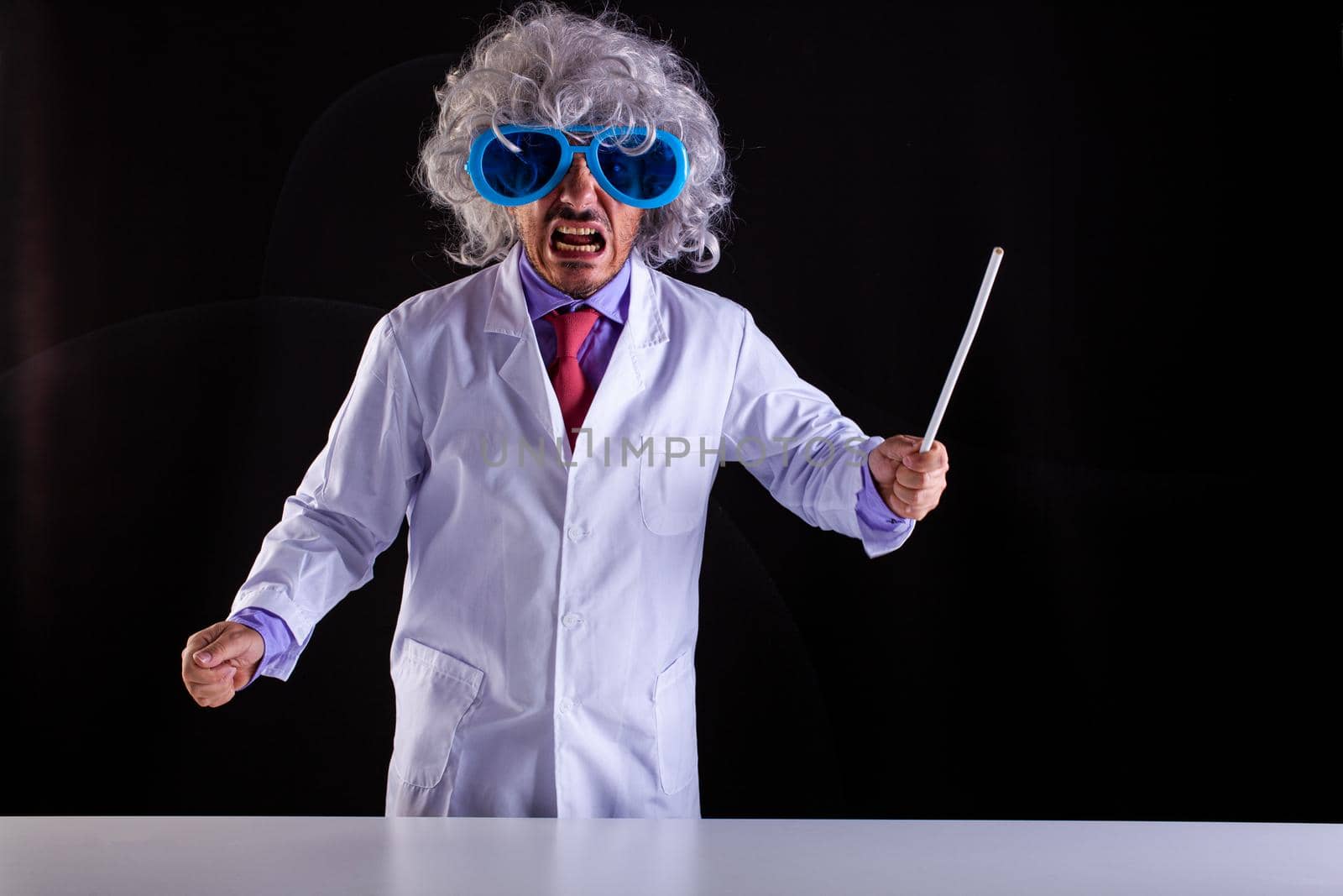 Crazy science teacher in white coat with unkempt hair in funny eye glasses by bepsimage