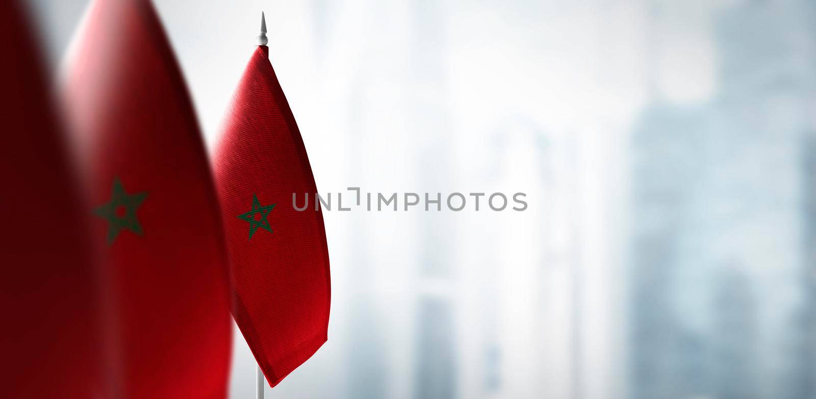 Small flags of Morocco on a blurry background of the city.