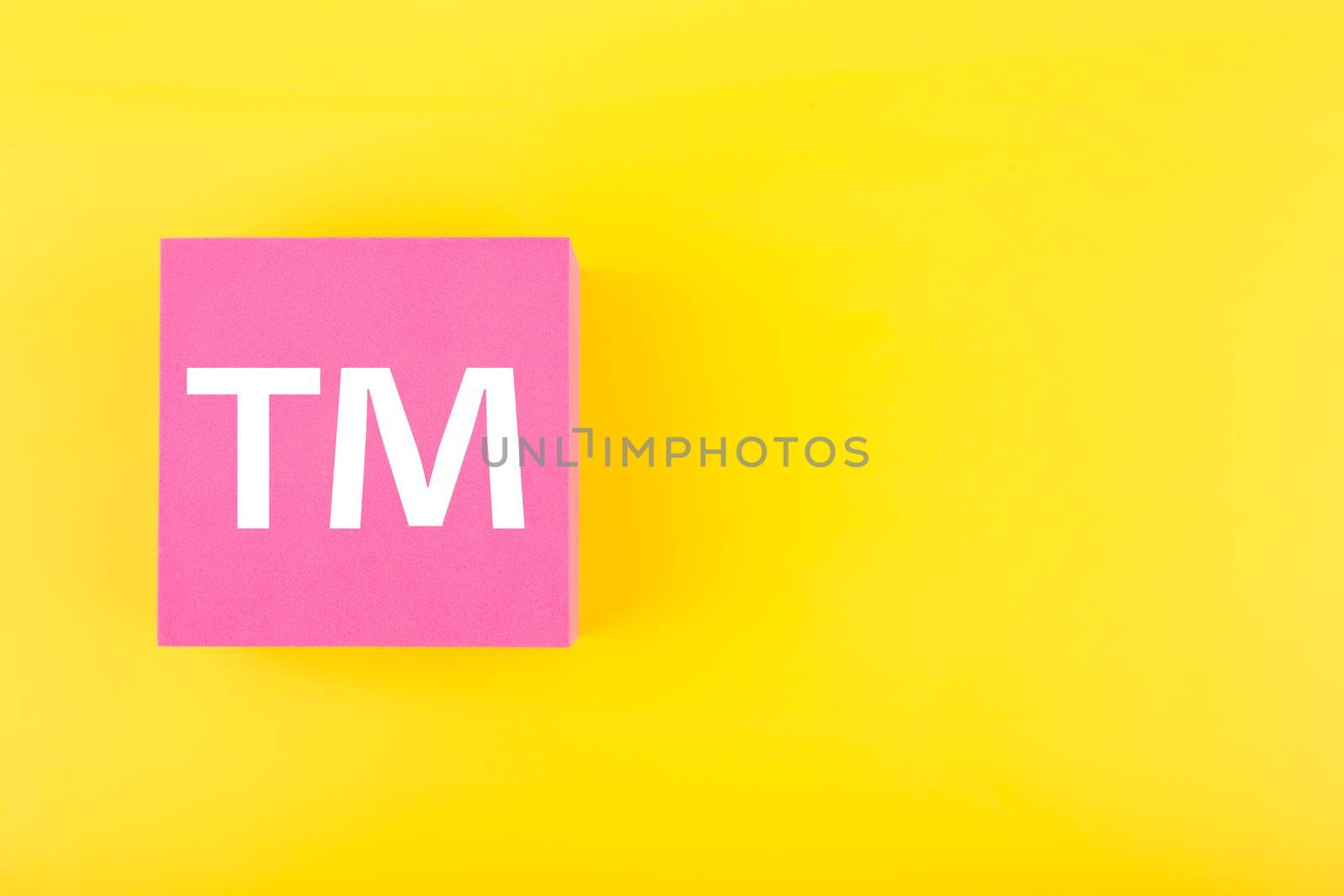 TM trademark sign on pink figure on yellow background with copy space. Concept of intellectual property registration and protection