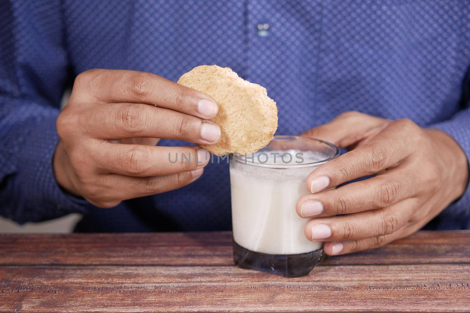 young man eating cookies and glass of milk on table by towfiq007