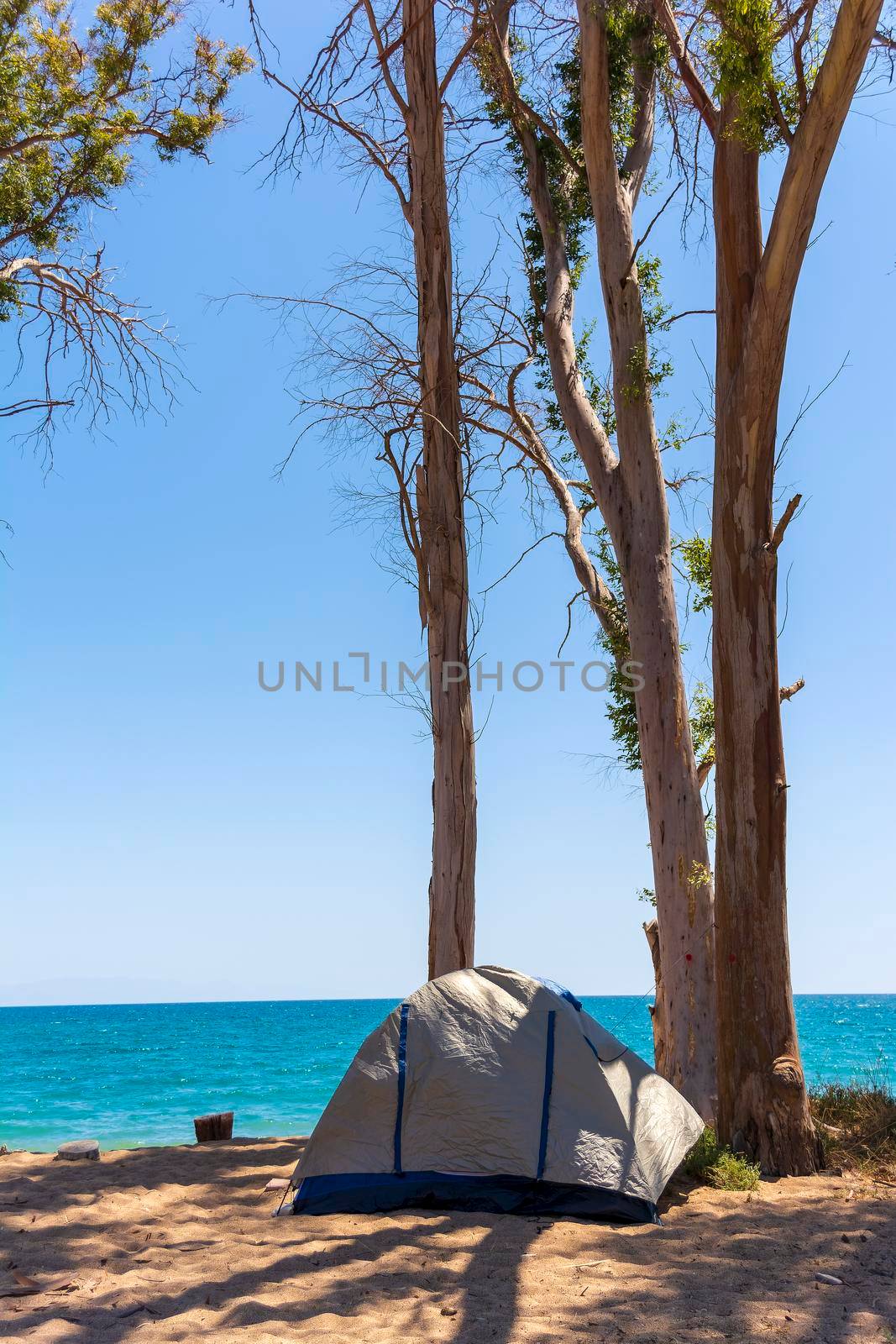 Tourist tent on sandy beach near the blue sea at Velika beach, Messinia. Greece. Camping on sandy beach.