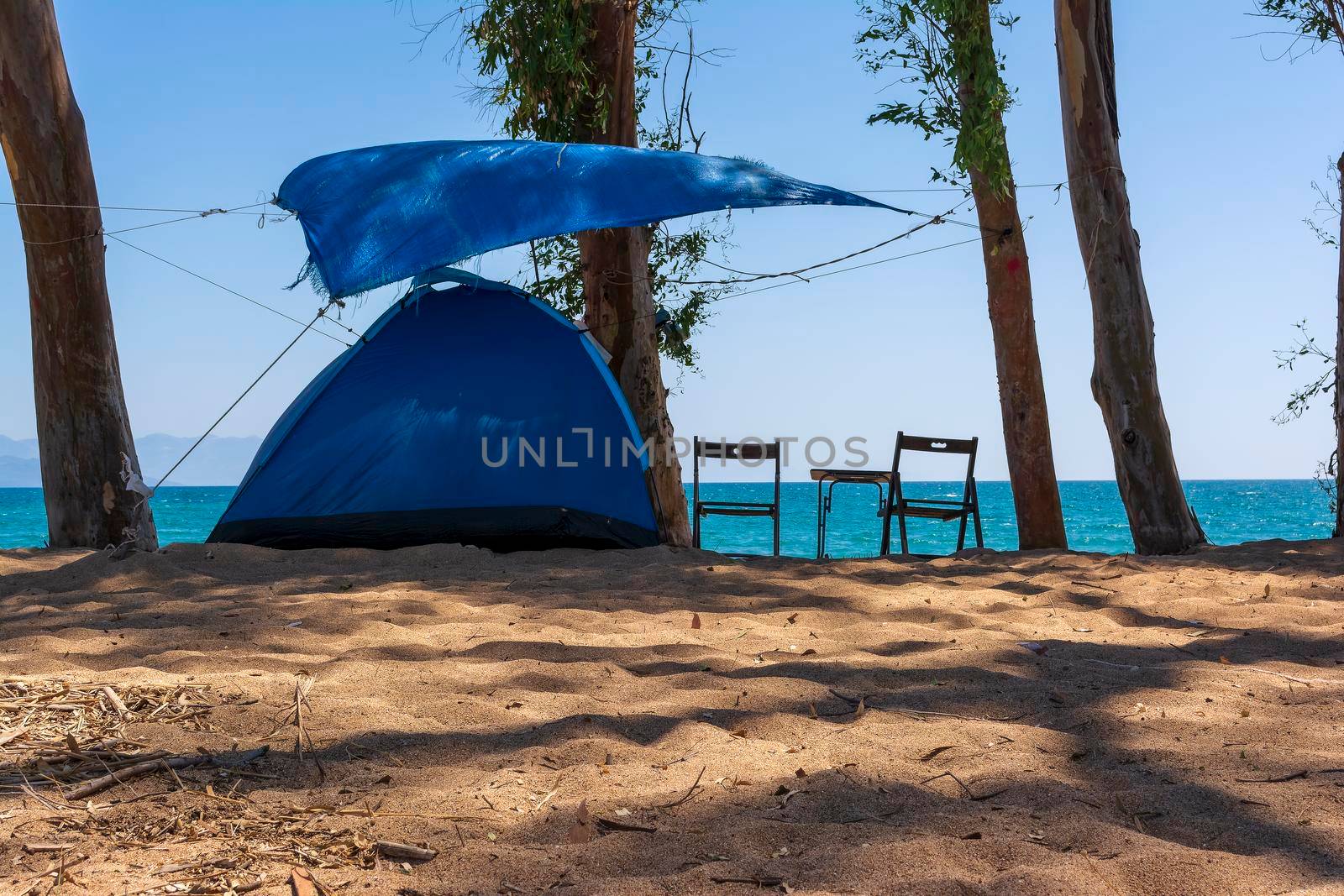 Tourist tent on sandy beach near the blue sea at Velika beach, Messinia. Greece. Camping on sandy beach.