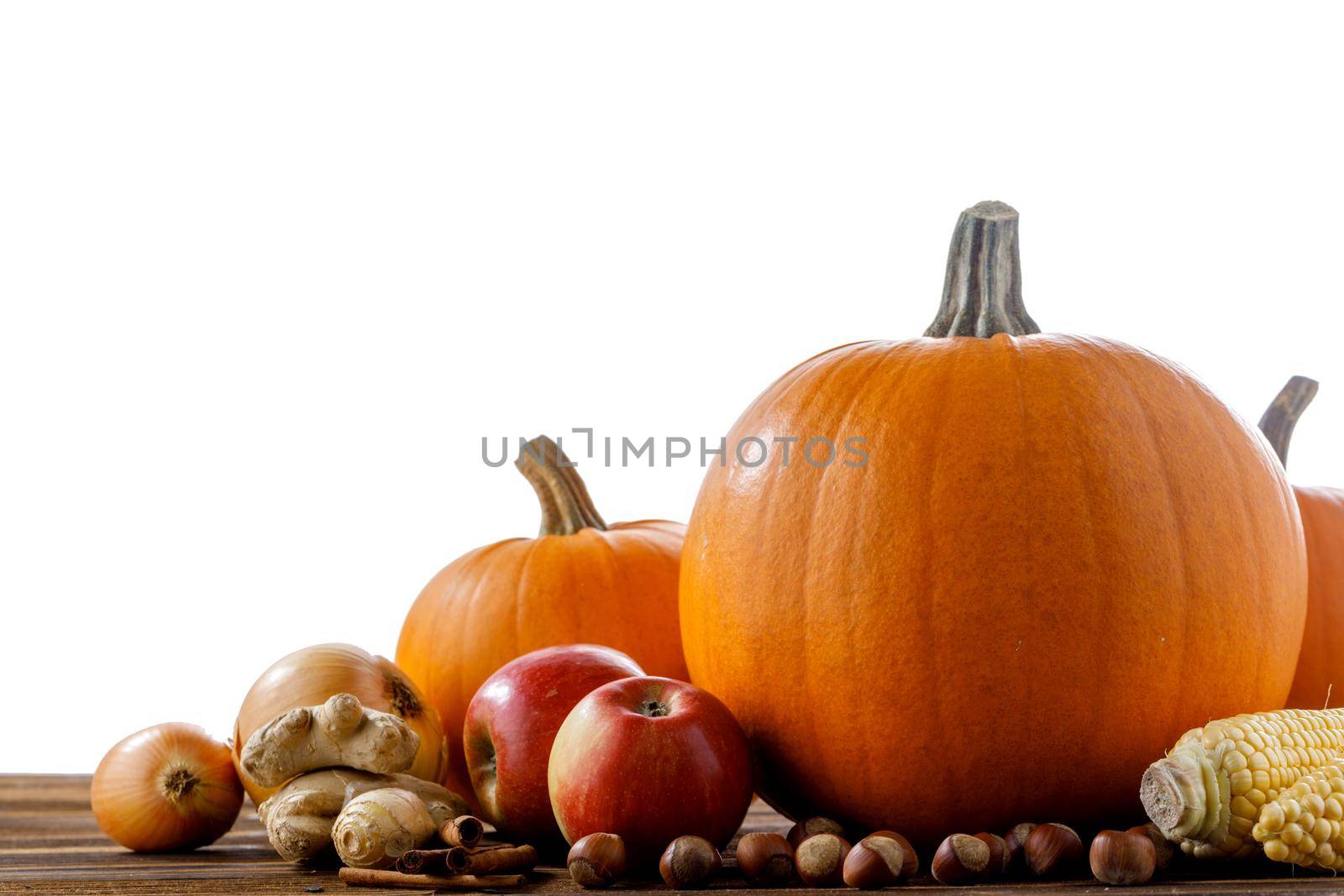 Autumn harvest on wooden table isolated on white background. Seasonal vegetables, fruits, pumpkin, apple, nuts, ginger, corn, onion cooking healthy food