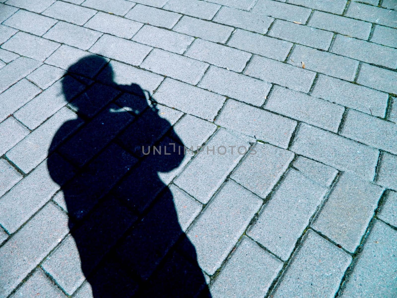 silhouette shadow of a girl with a camera on the background of road masonry. High quality photo