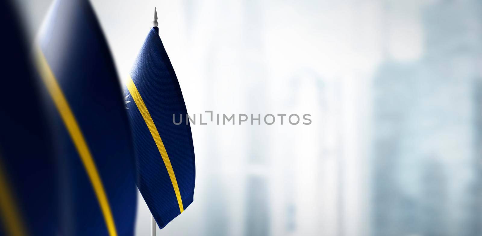 Small flags of Nauru on a blurry background of the city.