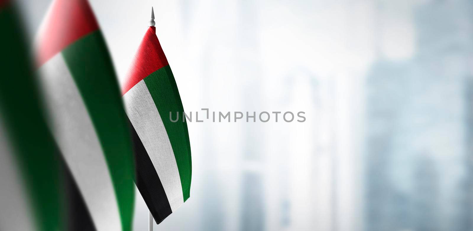 Small flags of United Arab Emirates on a blurry background of the city by butenkow
