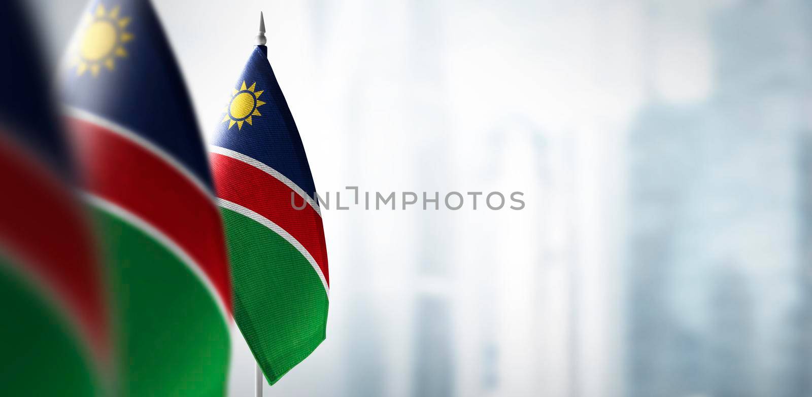 Small flags of Namibia on a blurry background of the city by butenkow