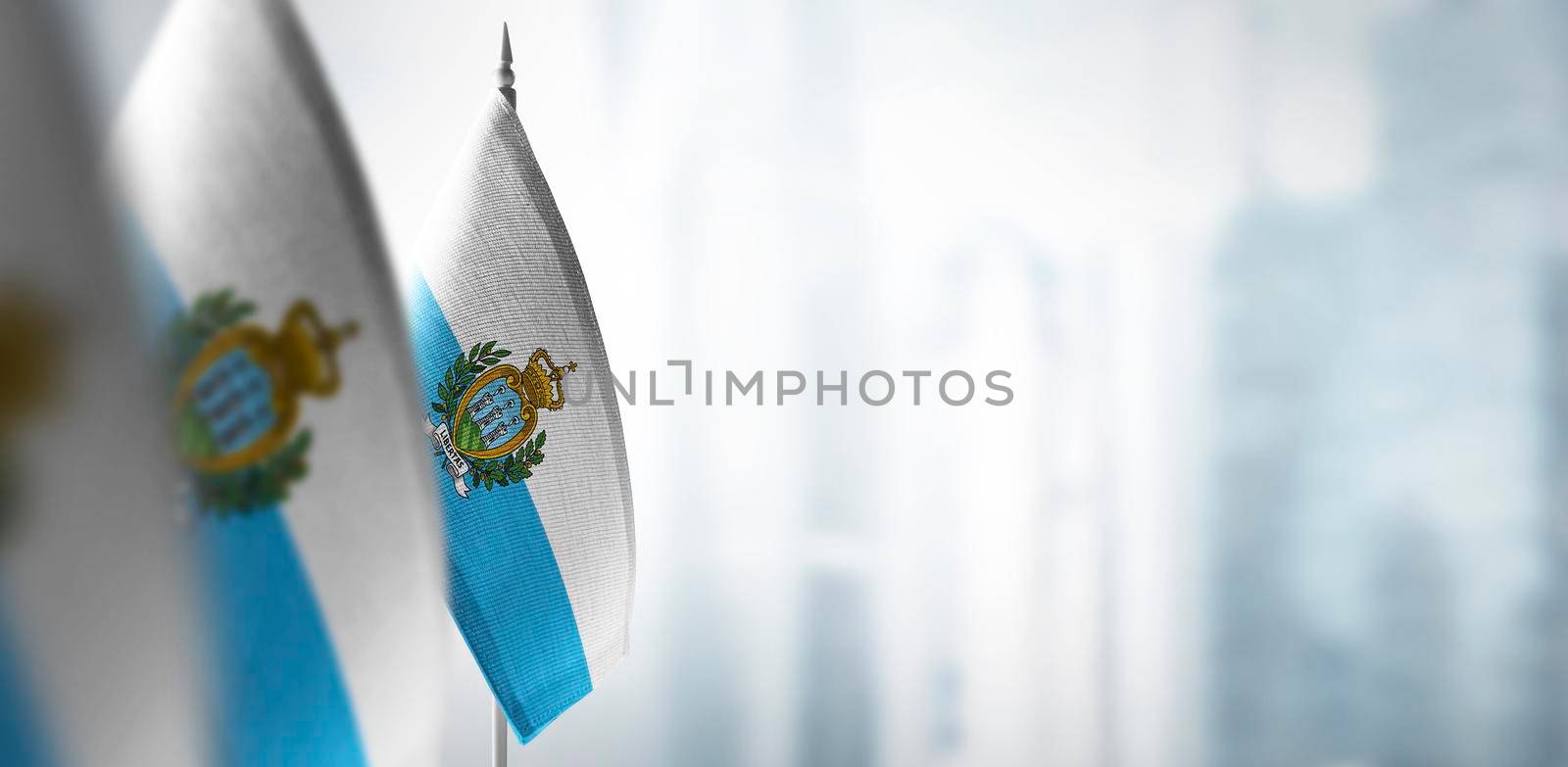 Small flags of San Marino on a blurry background of the city.