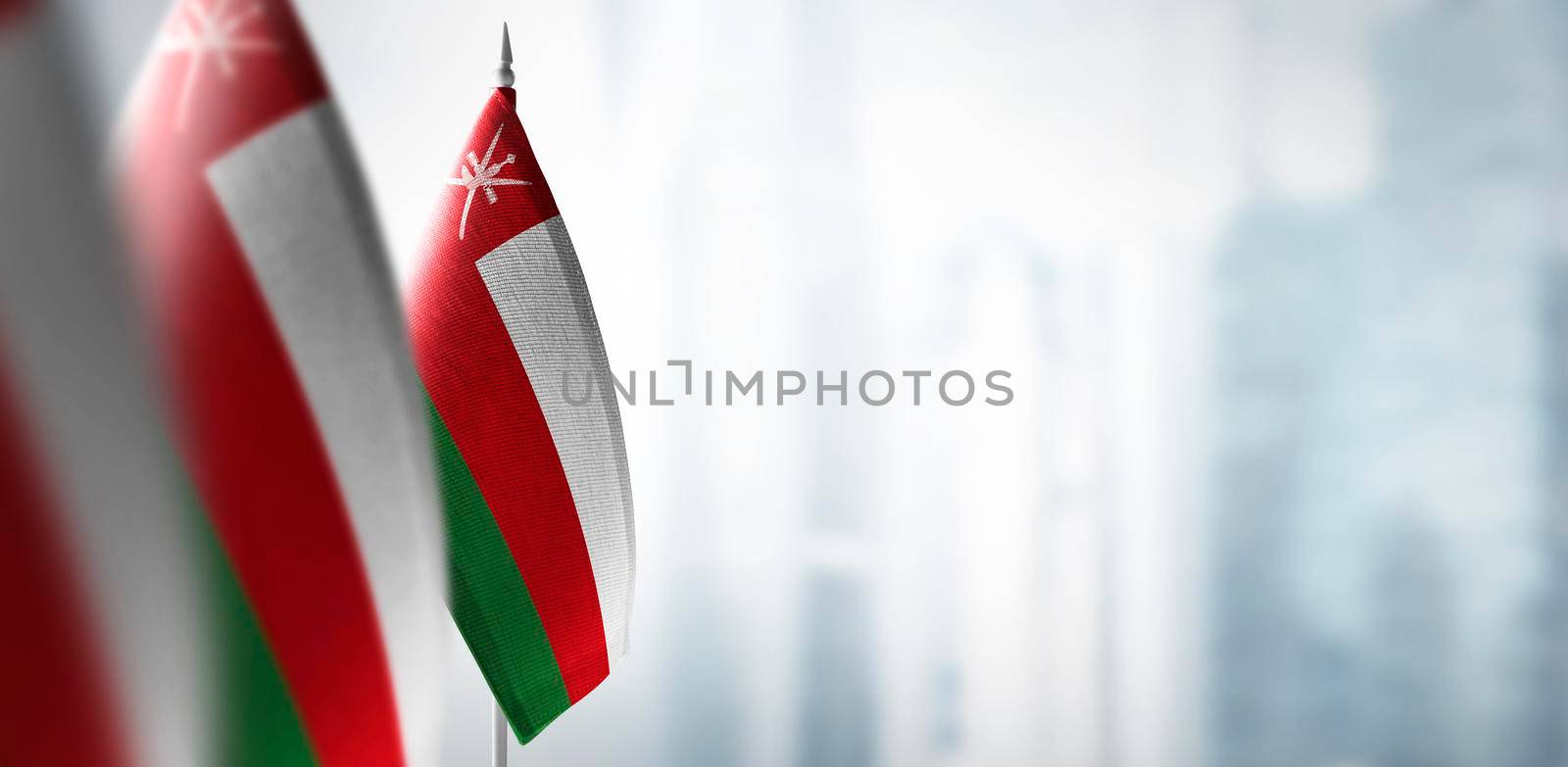 Small flags of Oman on a blurry background of the city.