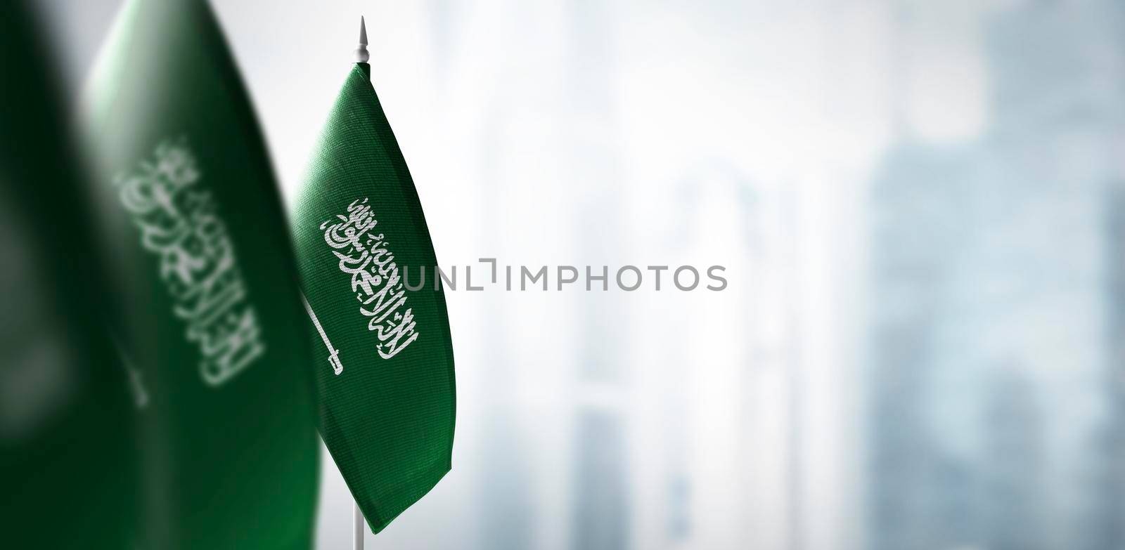 Small flags of Saudi Arabia on a blurry background of the city.