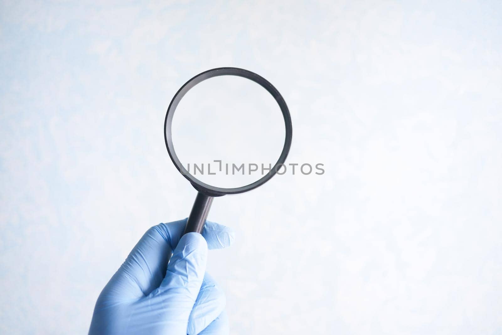 hand holding magnifying glass against white .