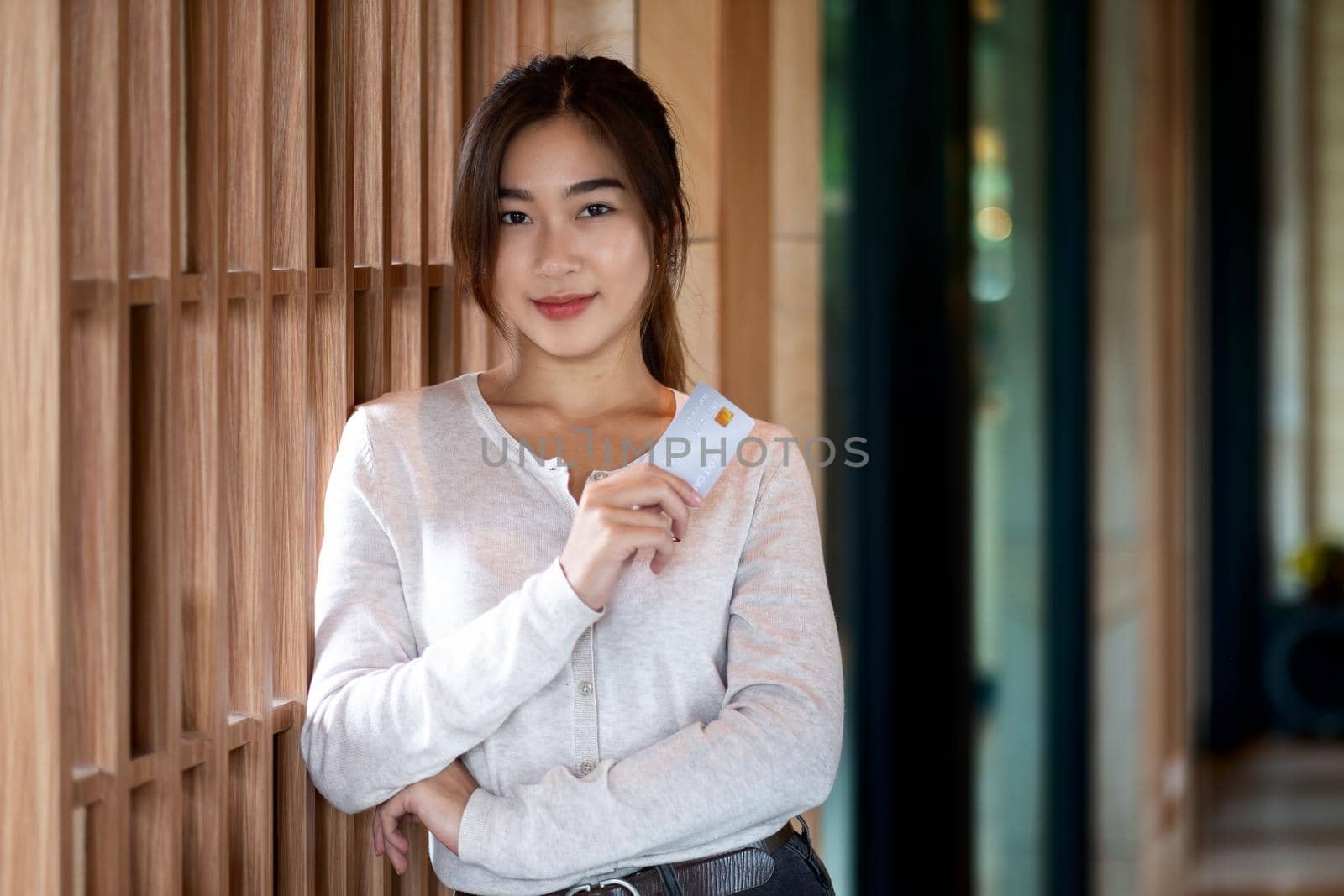 Portrait of young asian girl showing credit card and looking at camera,