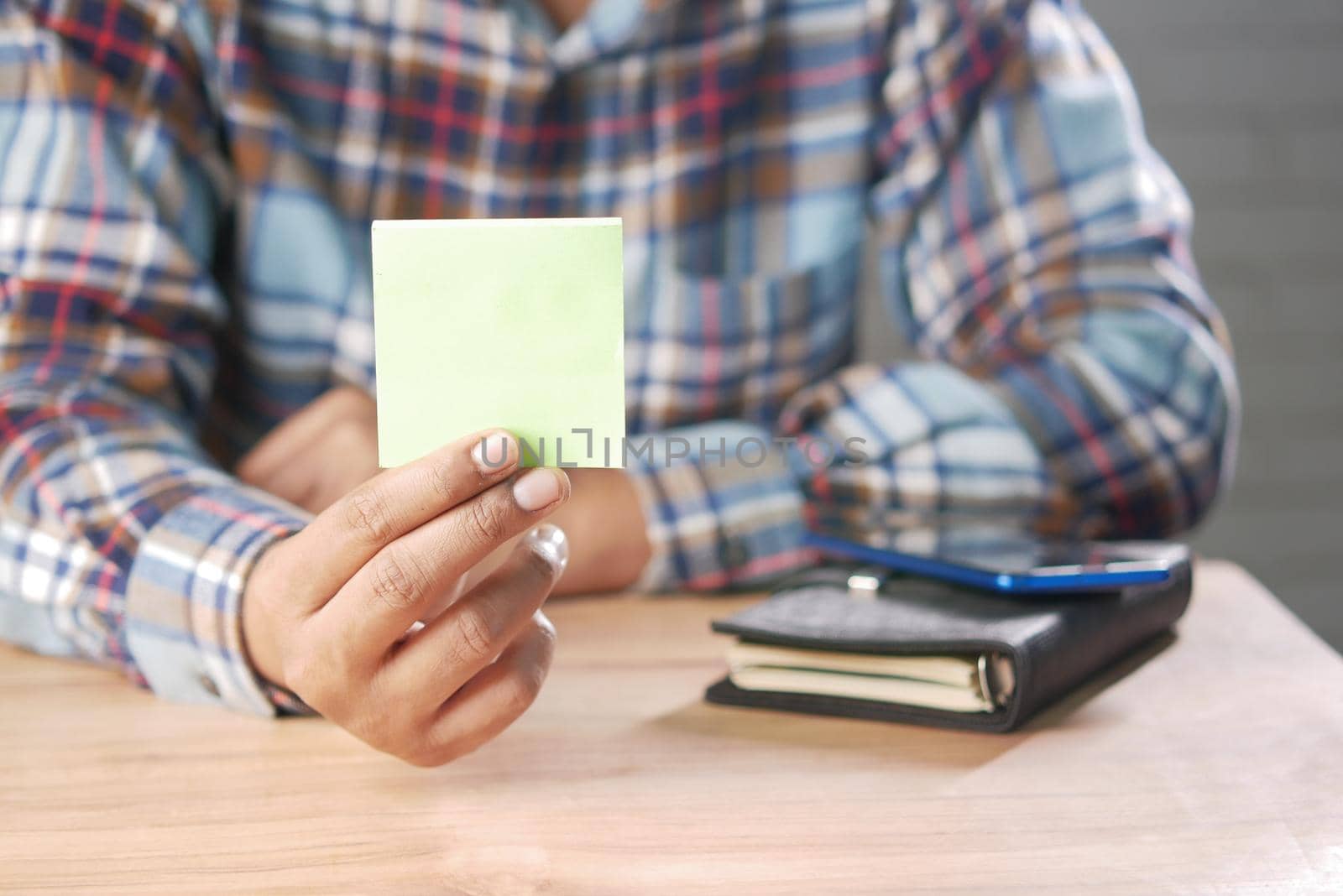 man hand hold a sticky note while sited ,
